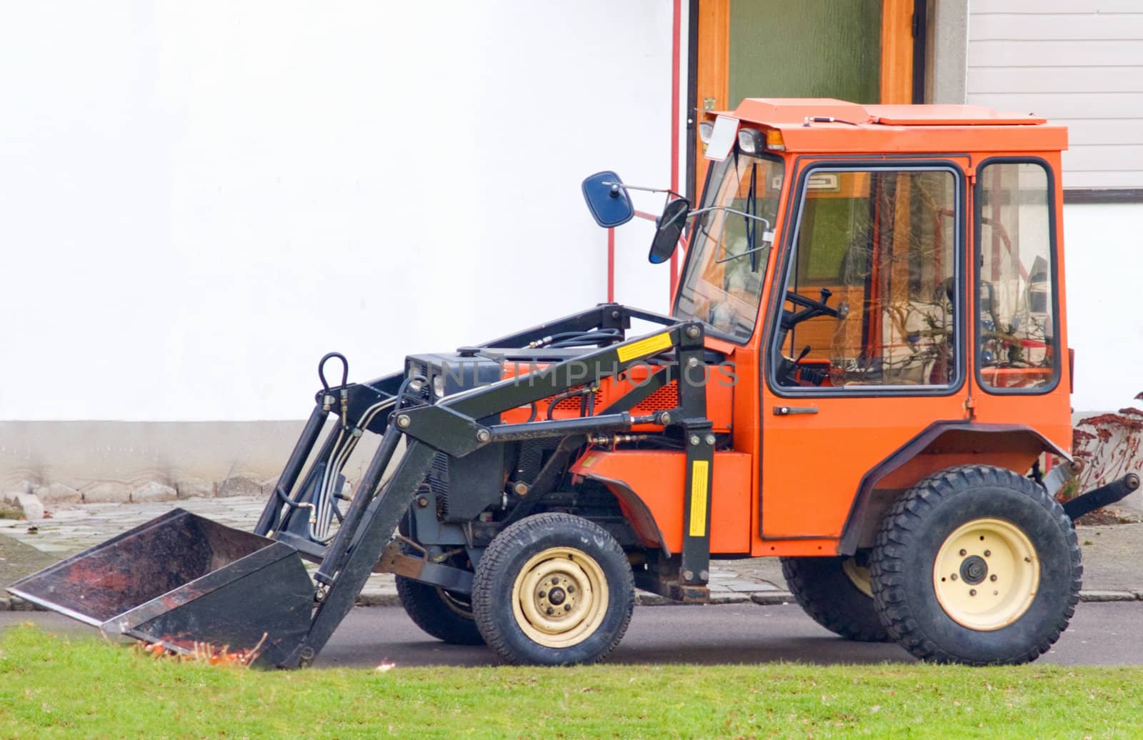 Orange tractor with scoop bucket  in the suburbs