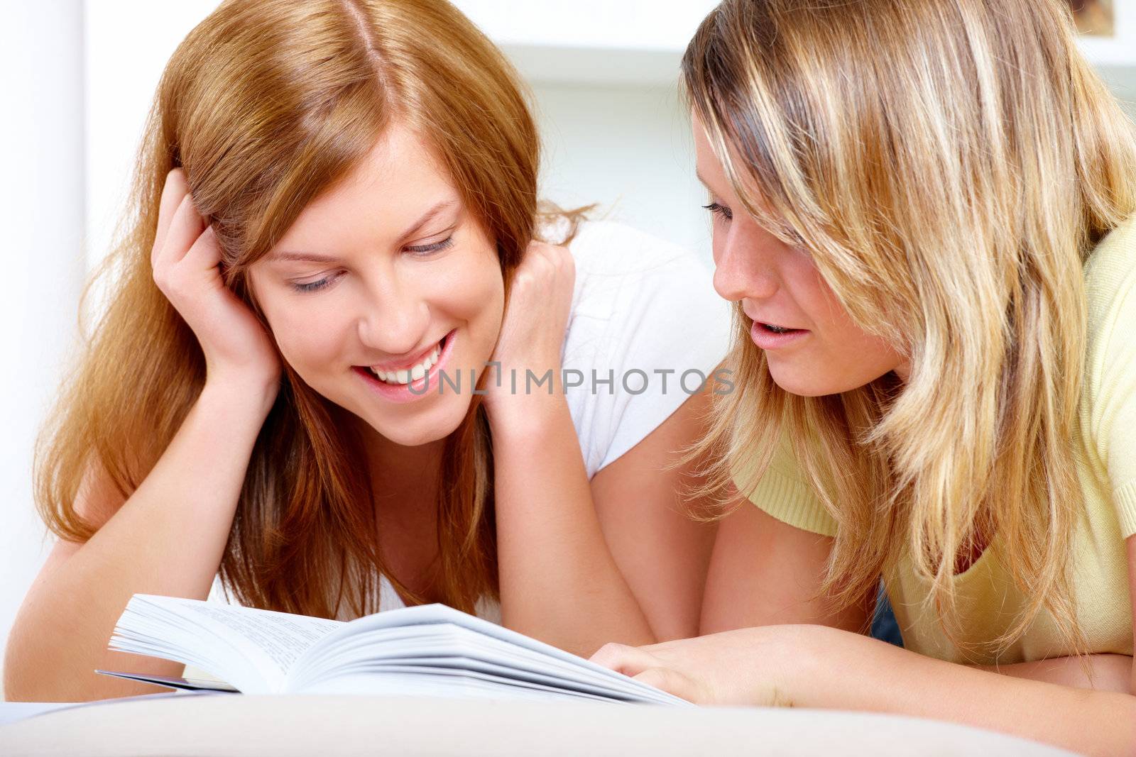 Beautiful happy girls laying and reading book