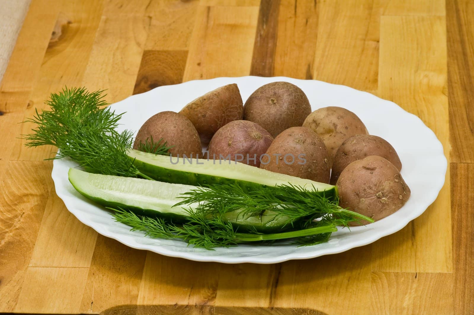 Provincial still-life with boiled potatoes, sliced salt cucumber and some dill on white porcelain  plate