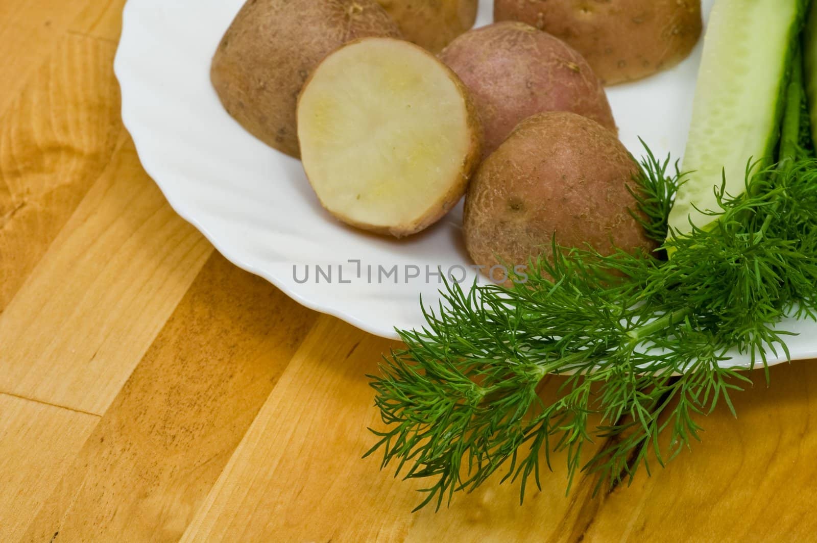 Provincial still-life with boiled potatoes, sliced salt cucumber and some dill on white porcelain  plate