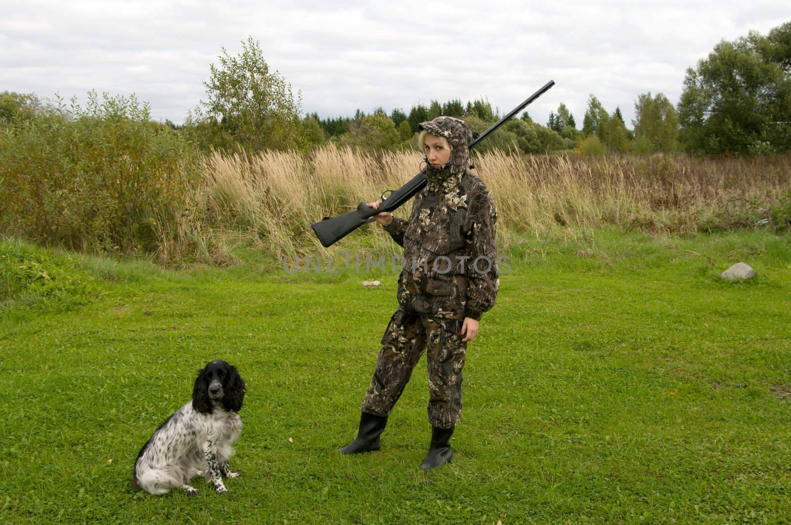 Blonde in camouflage with a gun and russian hunting spaniel.