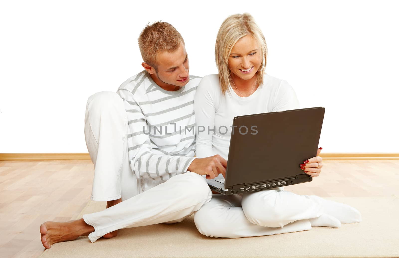 Portrait of a happy couple sitting on the floor with laptop