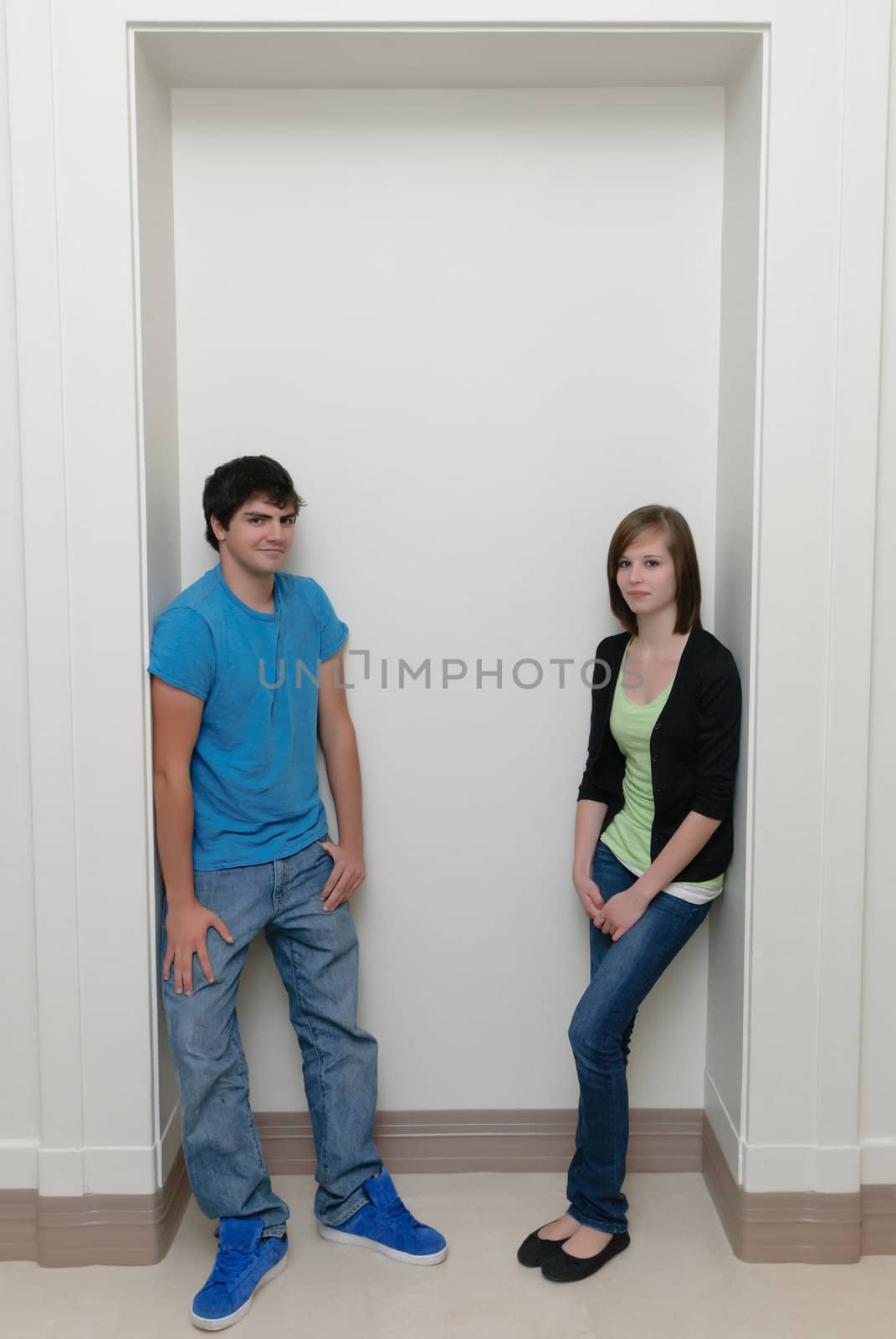 Two teenagers leaning  in an alcove with copyspace above.