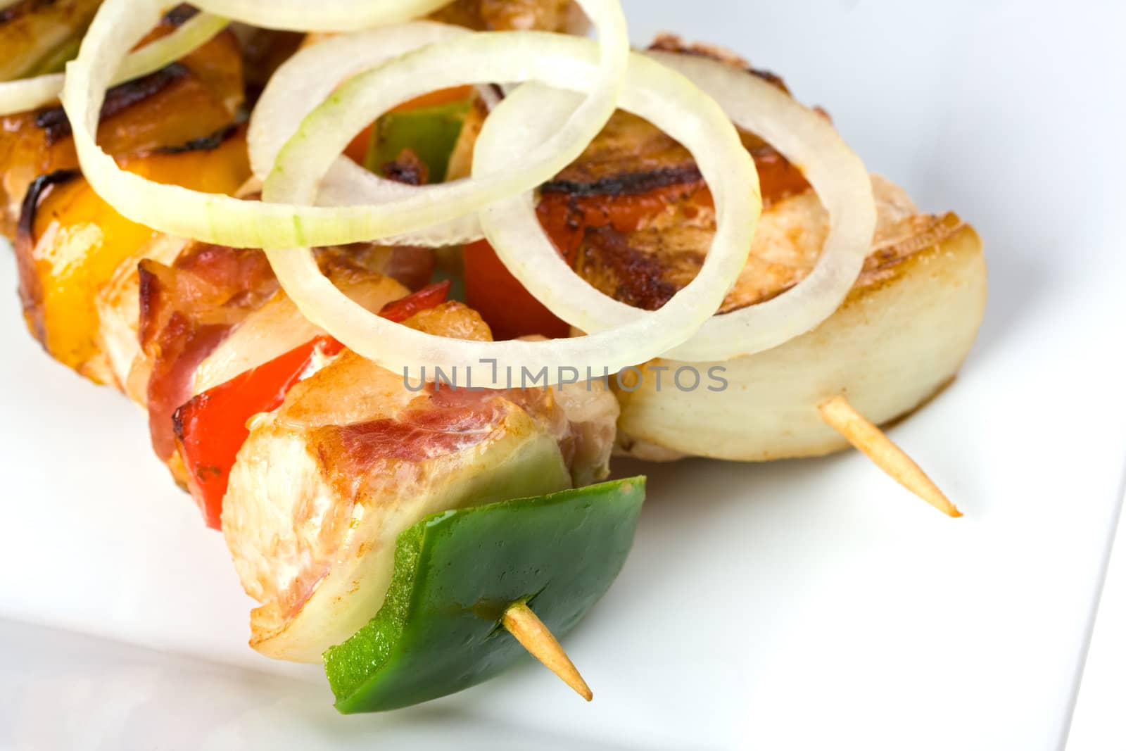 shashlik on a plate with a tomato and salad leaf