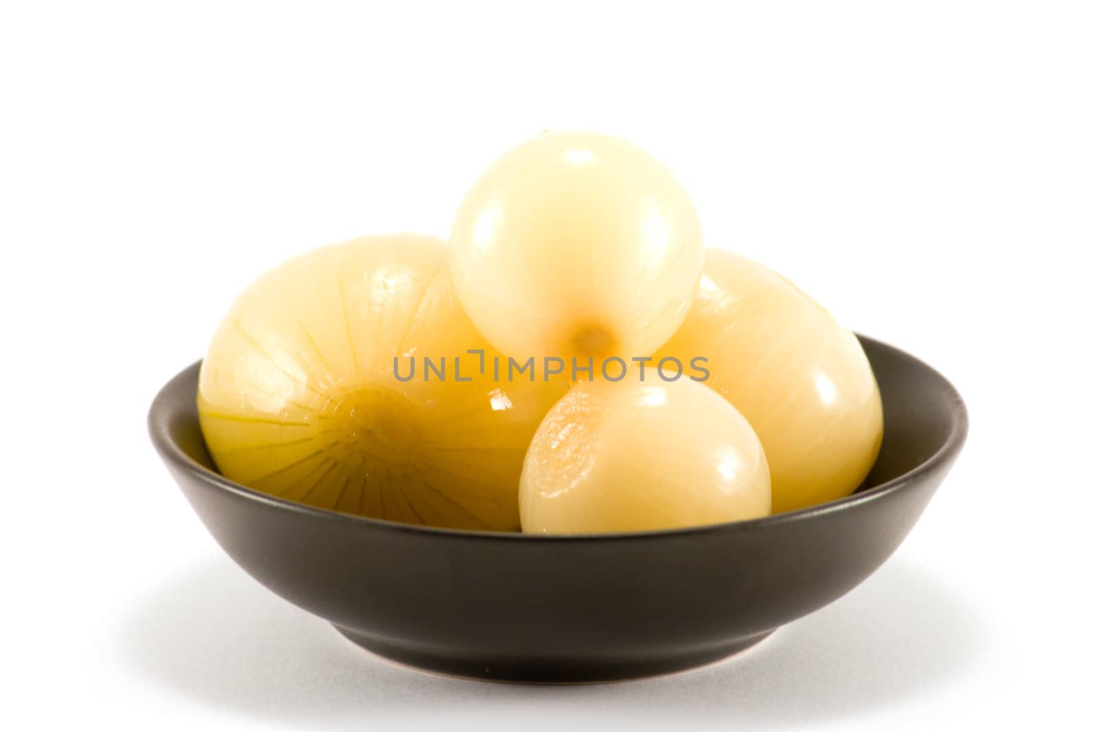 Four Pickled onions in a small black bowl on a white background