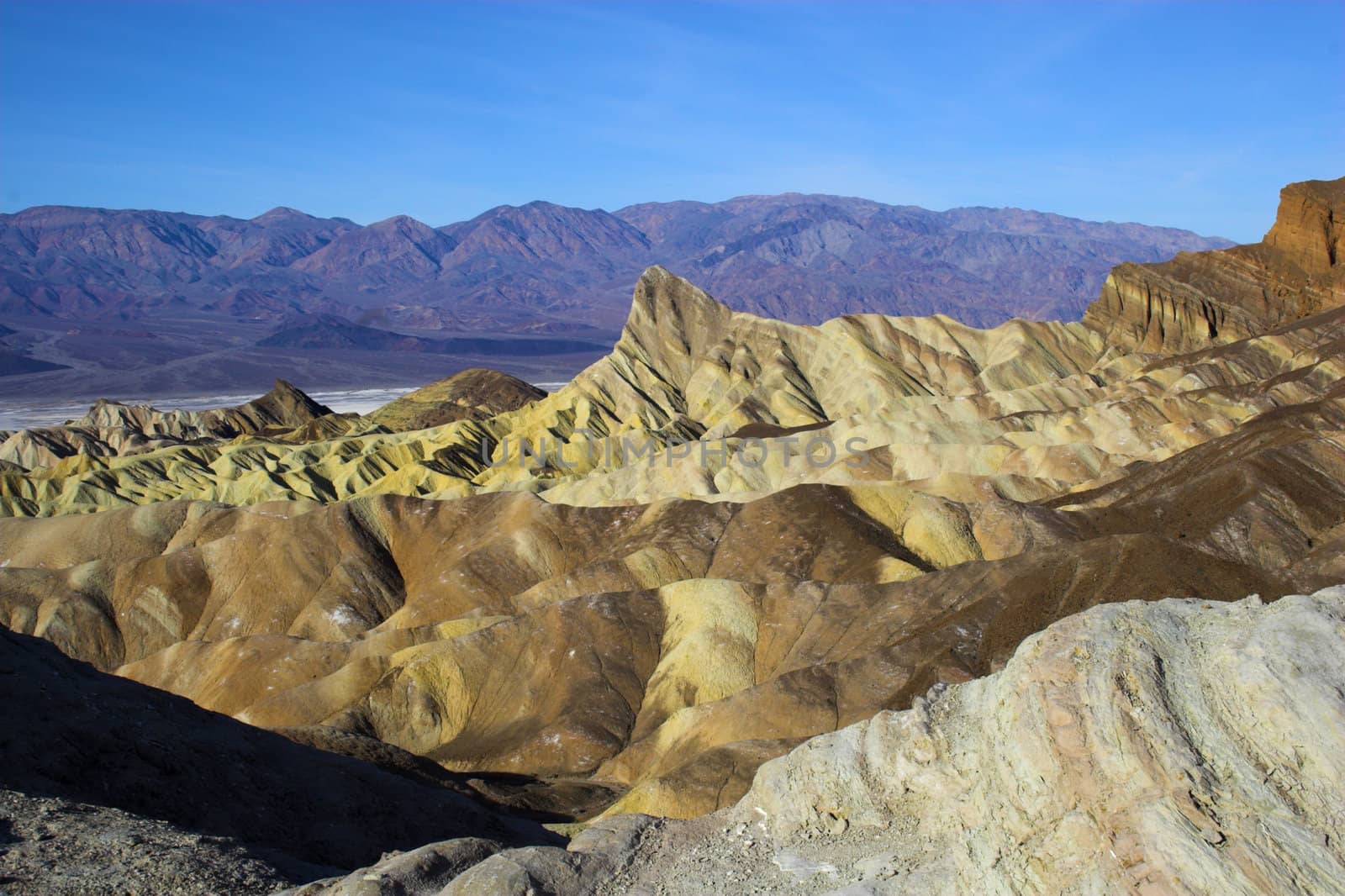 Desert landscape with multicolored yellow clay and salt mineral deposits in geological formations of Death Valley National Park