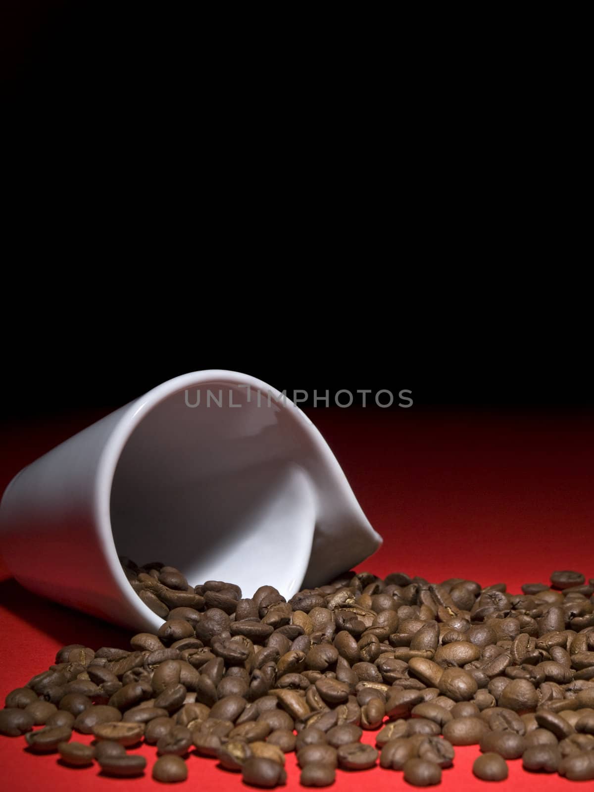 A fallen cup with coffee beans spread out.
