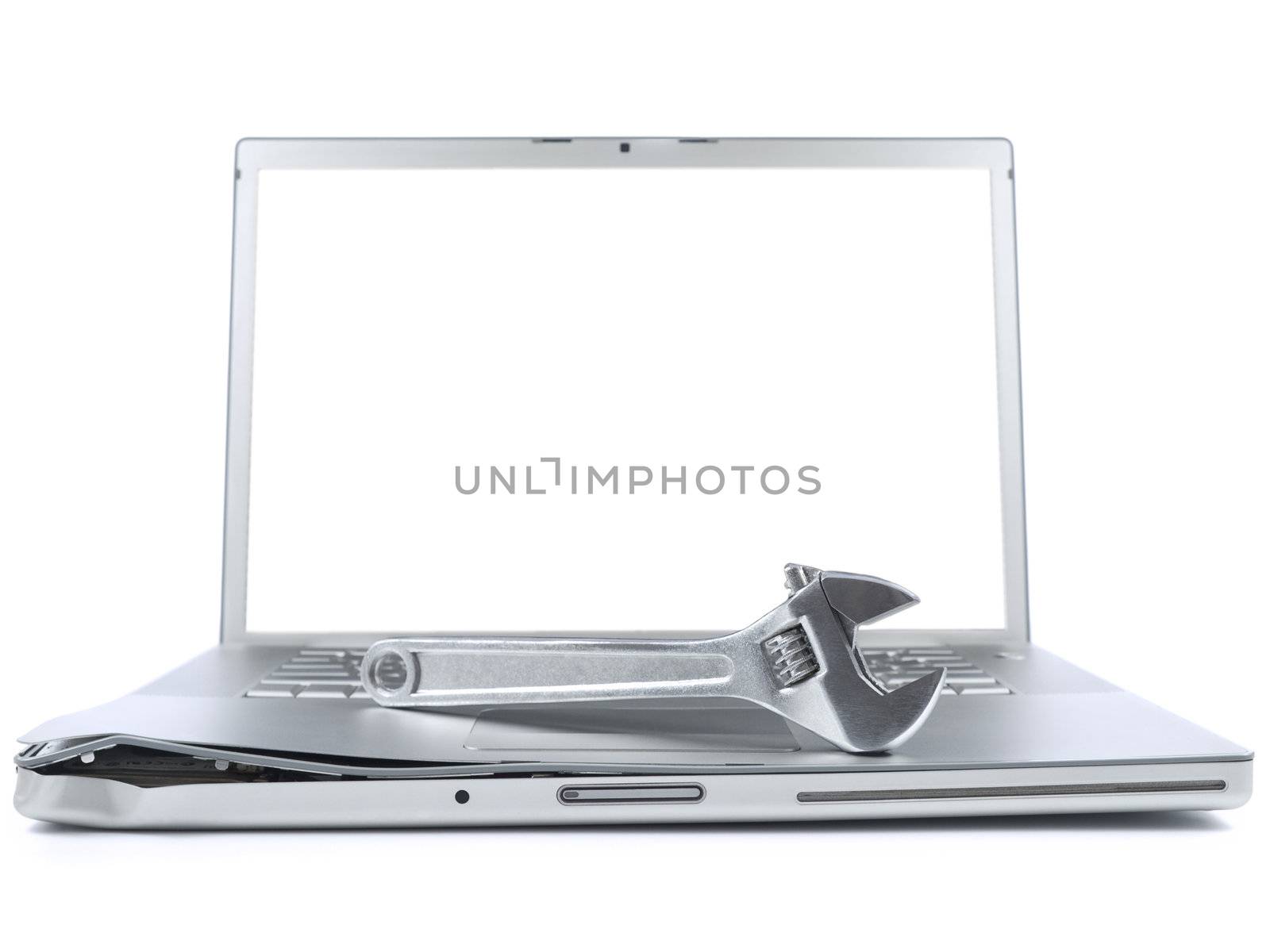 A spanner over a damaged laptop isolated over white background. White copy space on screen.