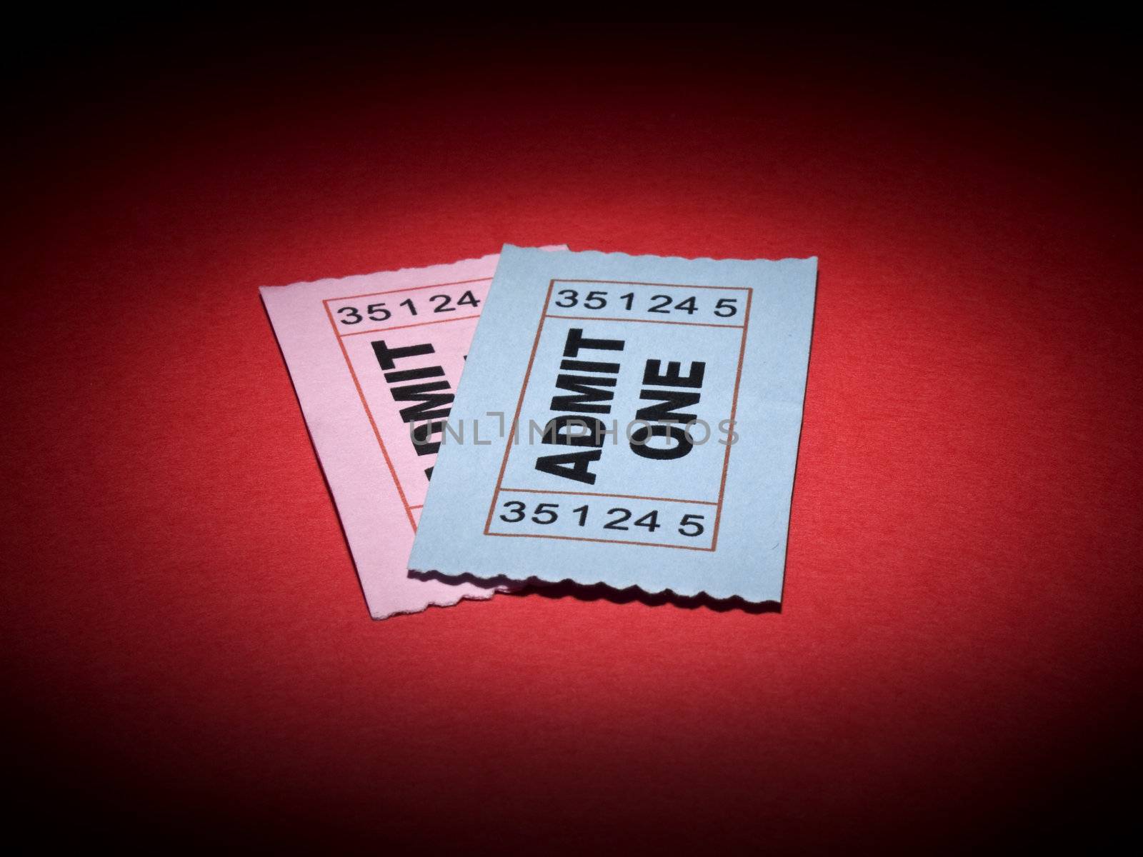 Close up shot of two generic admission tickets over red background.