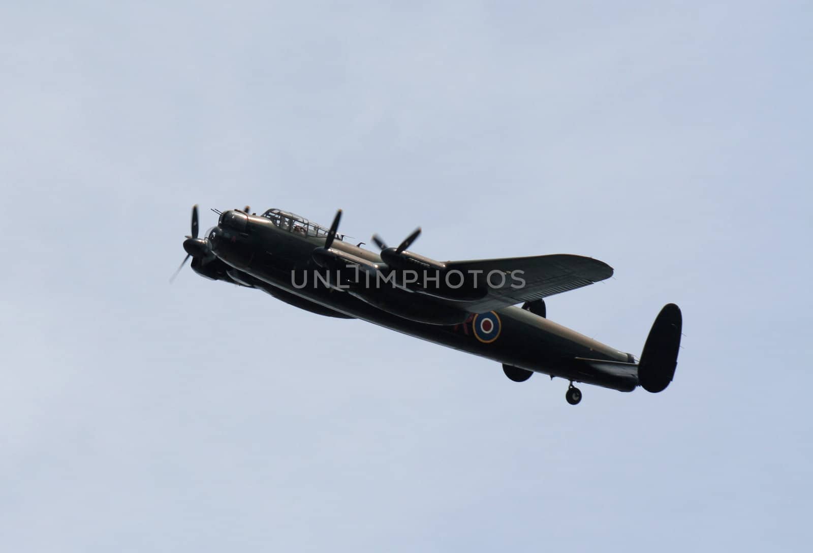 A Lancaster bomber soaring against a blue sky.
