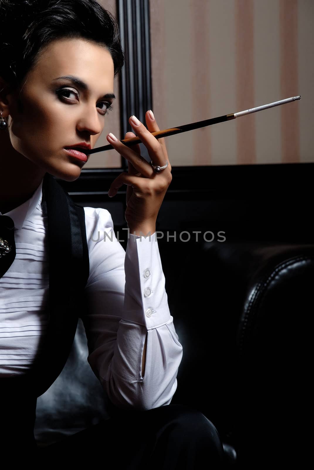 Woman on the striped background wearing business clothes, smoking.
