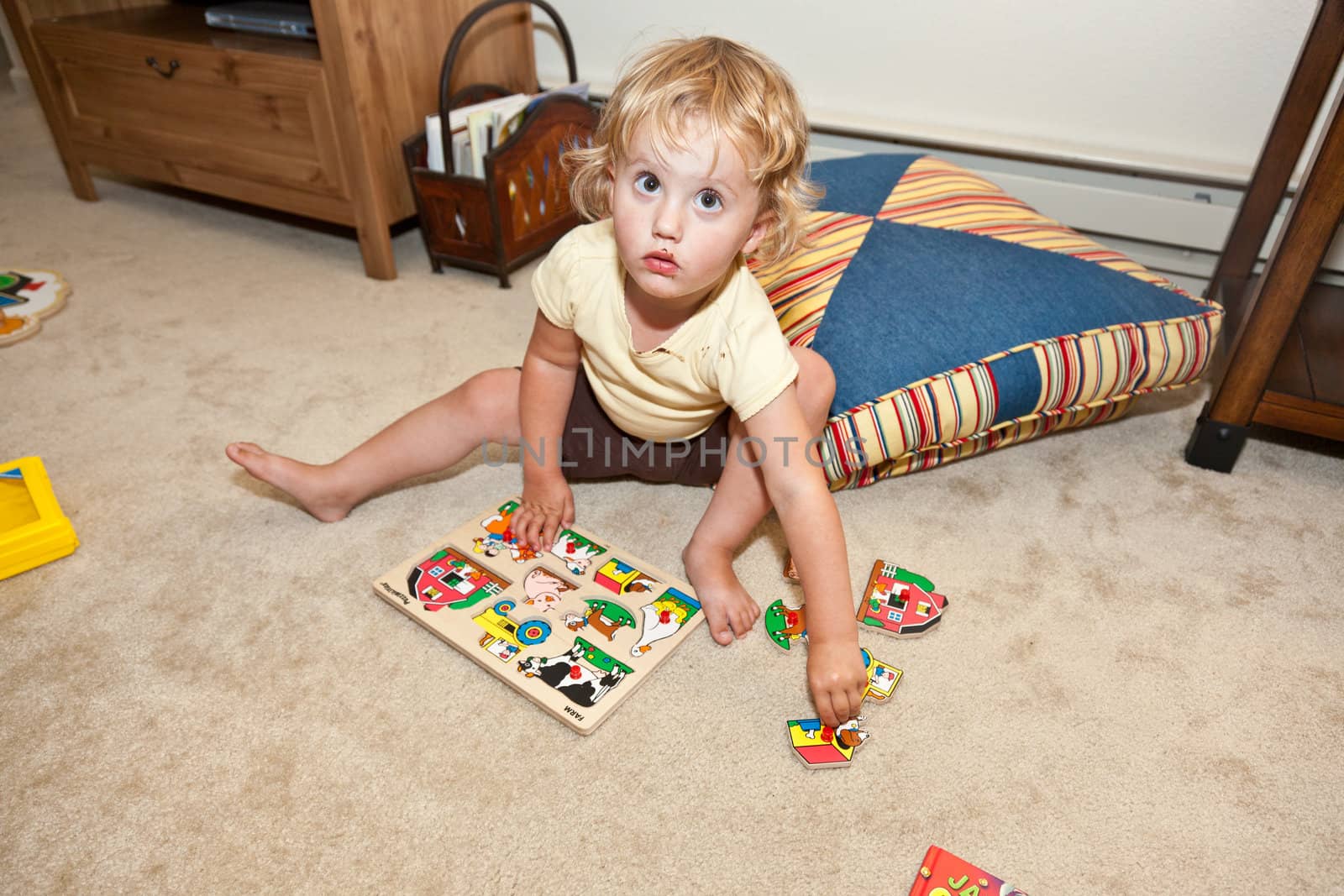 Cute little European toddler girl having fun with wooden puzzle.