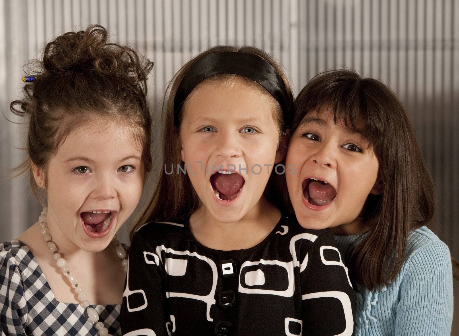 Closeup of three cute young girls screaming