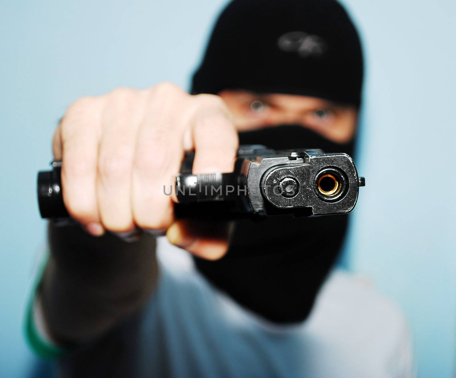 Young man holding up a gun with the focus on his gun