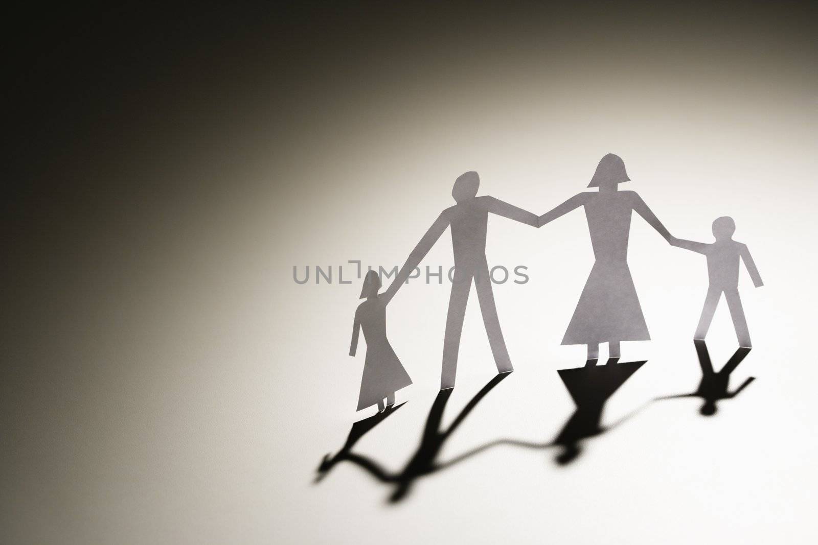 Paper cutout family of four standing holding hands.