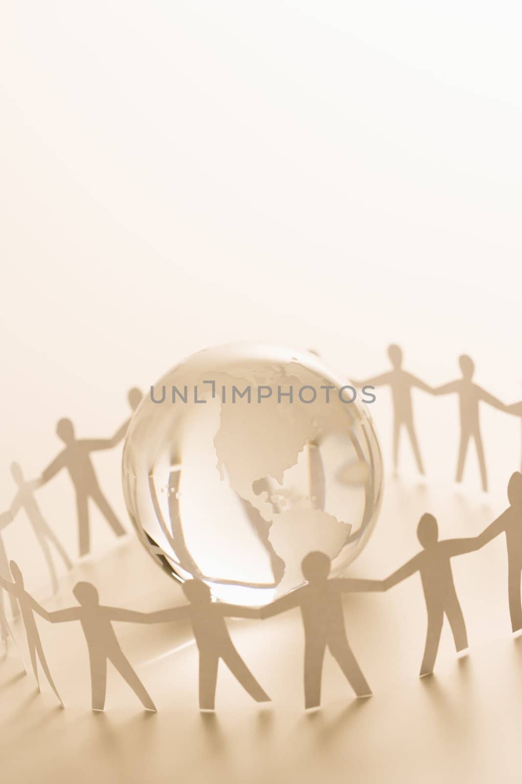 Cutout paper people standing around globe holding hands.