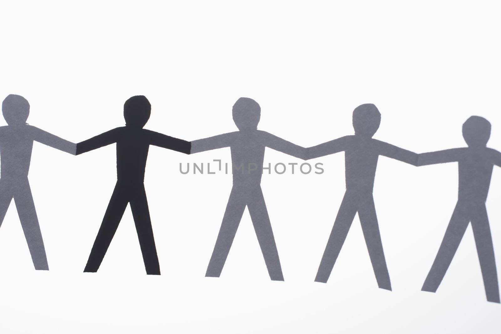 One black cutout paper person holding hands with group of white people.