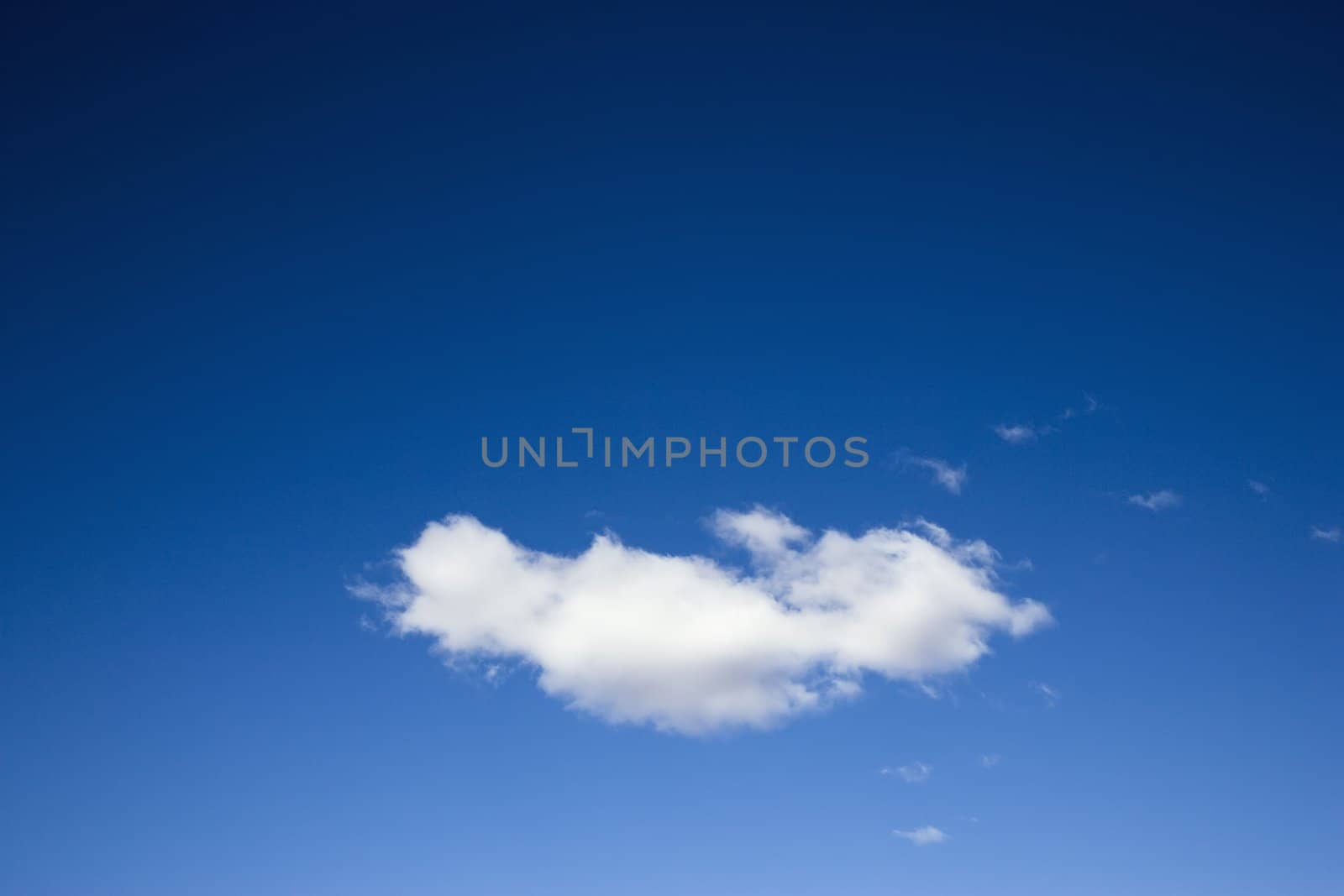 Single white fluffy cloud in blue sky.