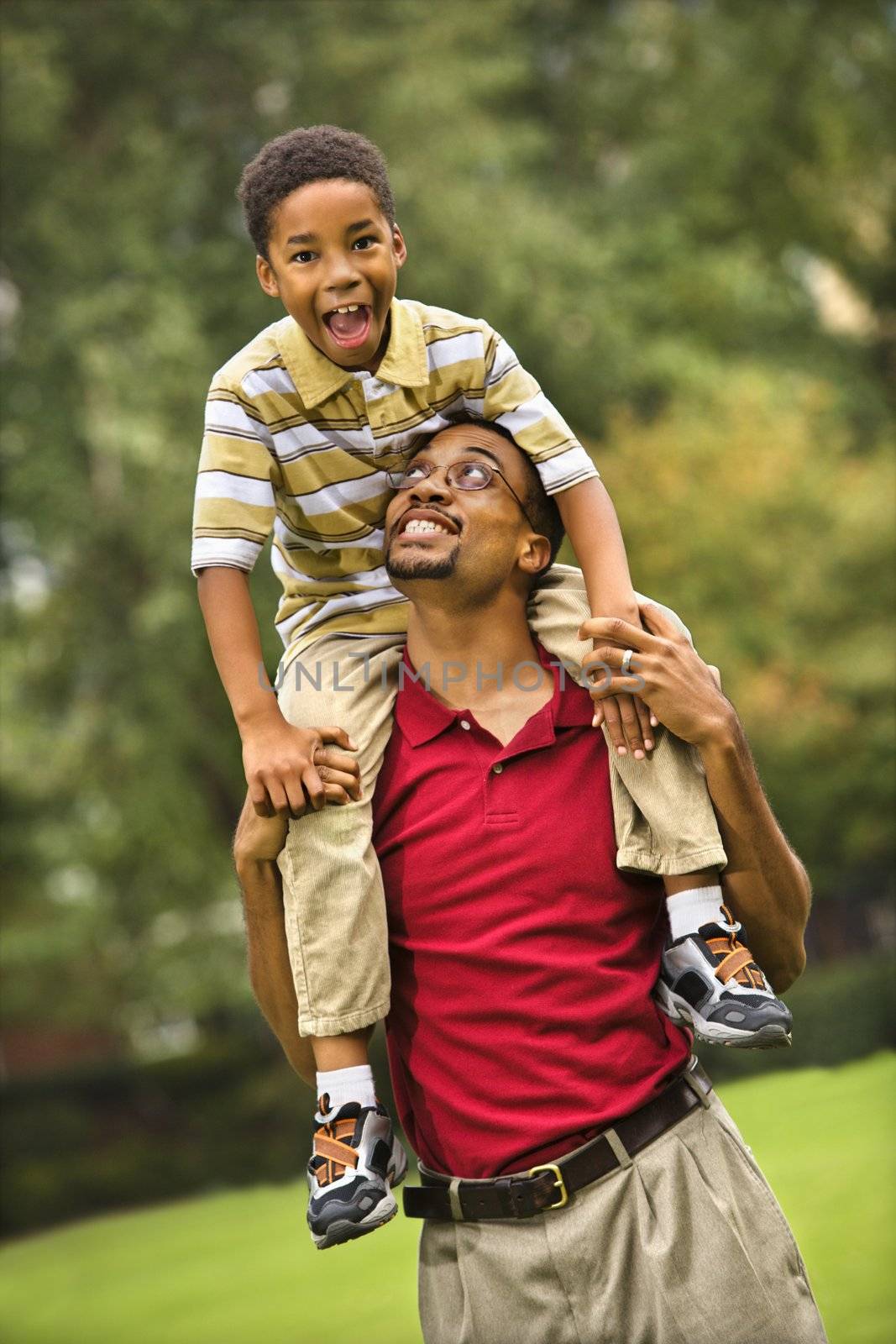 Father carrying his son on his shoulders smiling and looking at eachother.