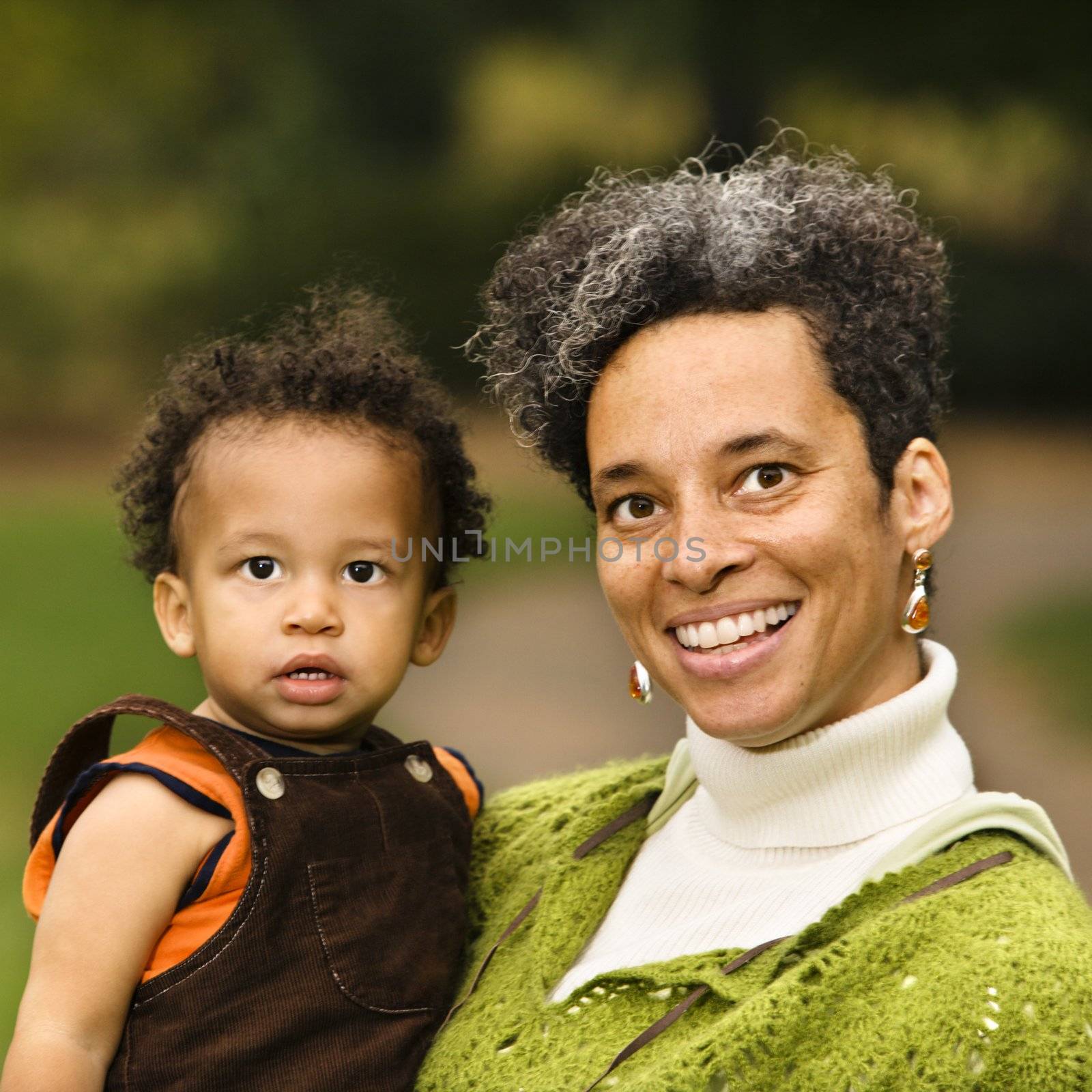 Head and shoulder portrait of woman holding boy and smiling.