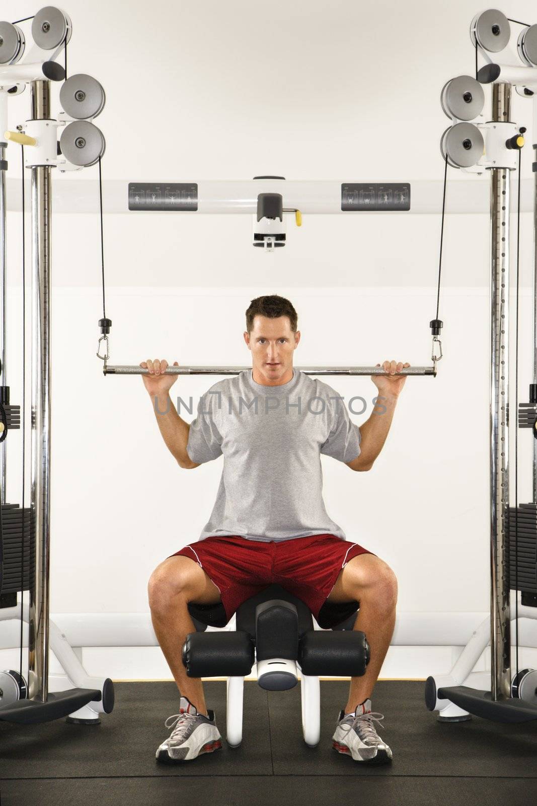 Man at gym lifting weights on weight machine.