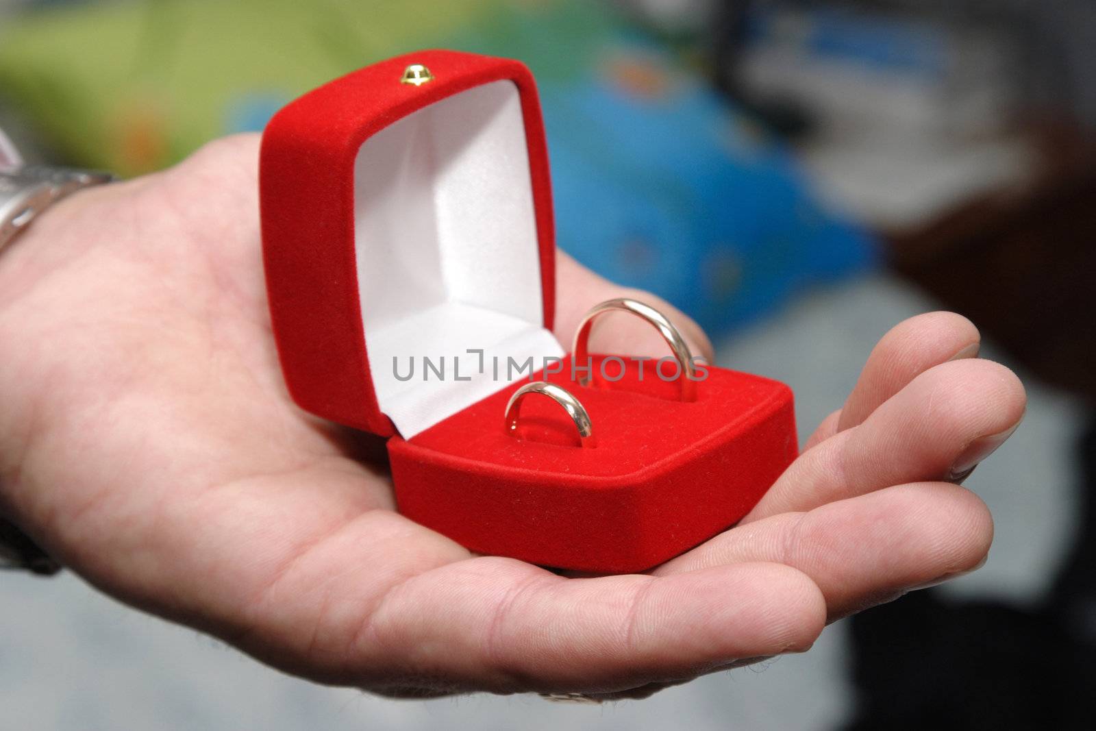 The man's hand holding a box with rings