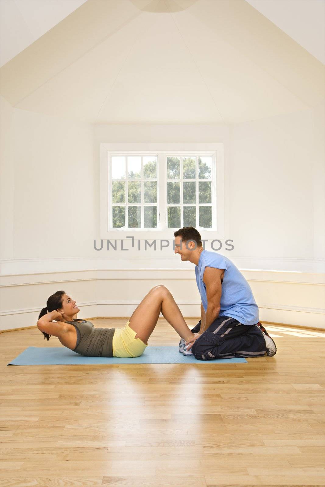 Man holding woman's feet down as she does sit up exercises.