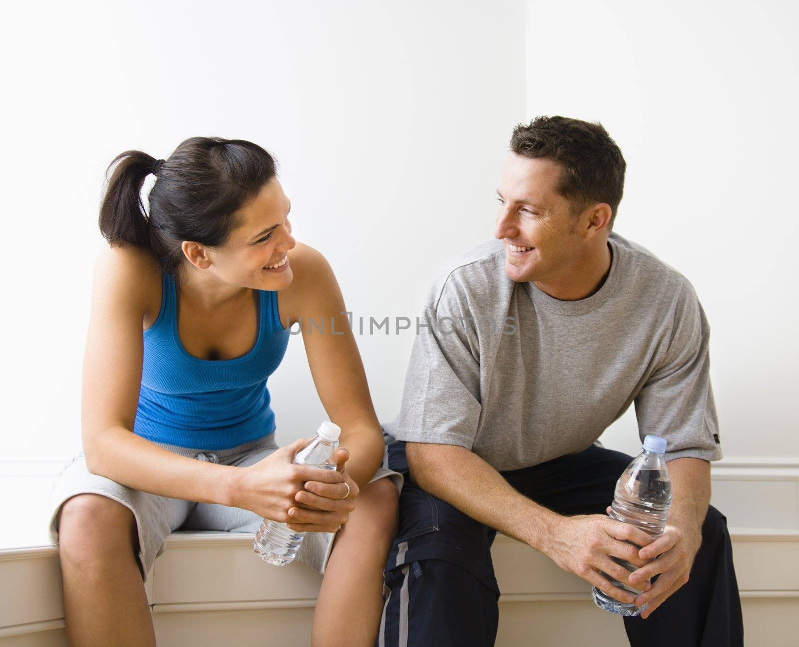 couple, eye contact, happy, portrait, smile, smiling, trainer, fit, physical, workout, fitness, health, gym, health club, hydration, bottle, bottled, water, break, sitting, wellness, recreation, lifestyle