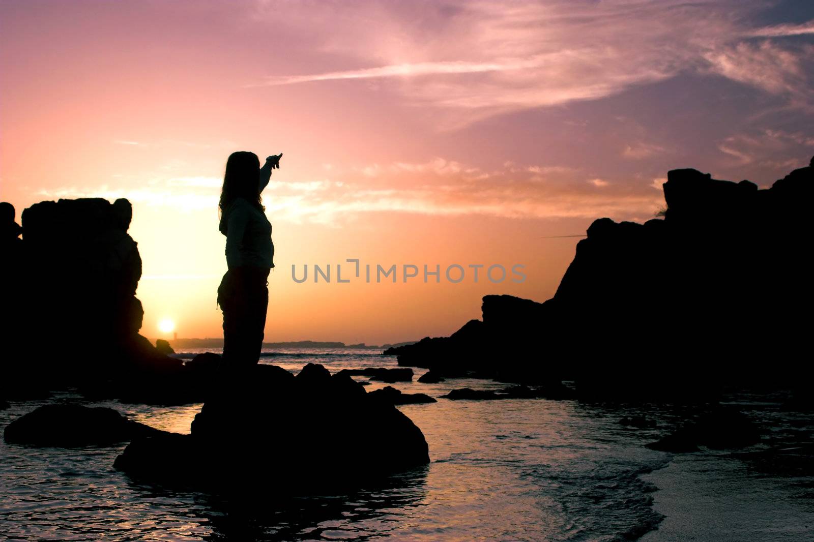 Woman silhouette appointing to the sunset