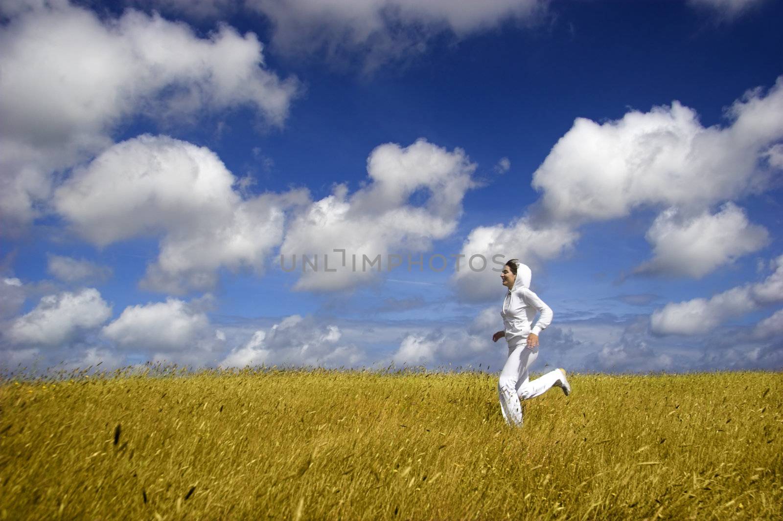 Beautiful woman running on a golden meadow