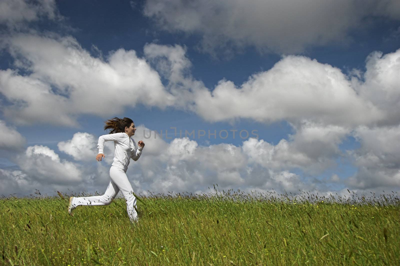 Beautiful woman running on a green meadow