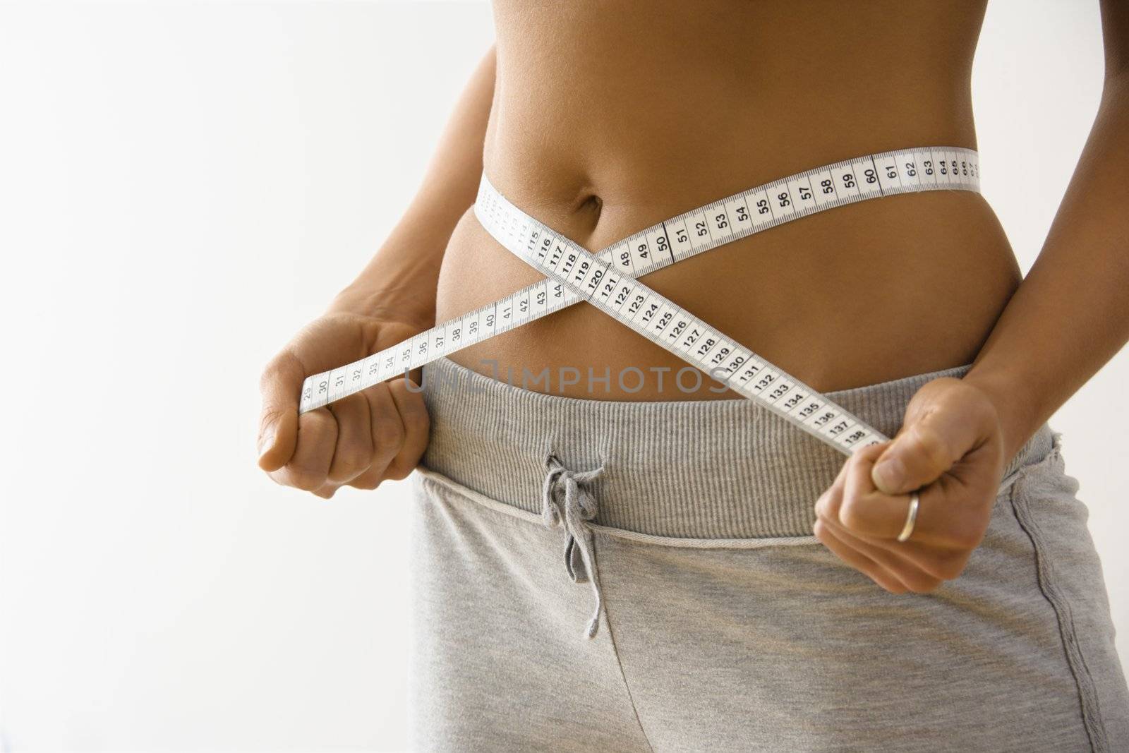 Woman standing pulling measuring tape around waist.