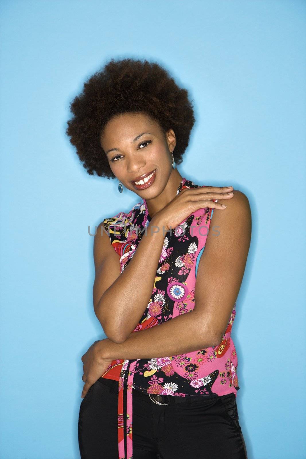 Woman with afro wearing vintage print fabric smiling.