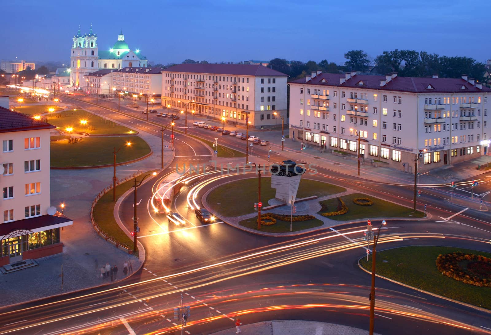 City centre at the night, the brisk movement of cars. On a background a cathedral church of Grodno