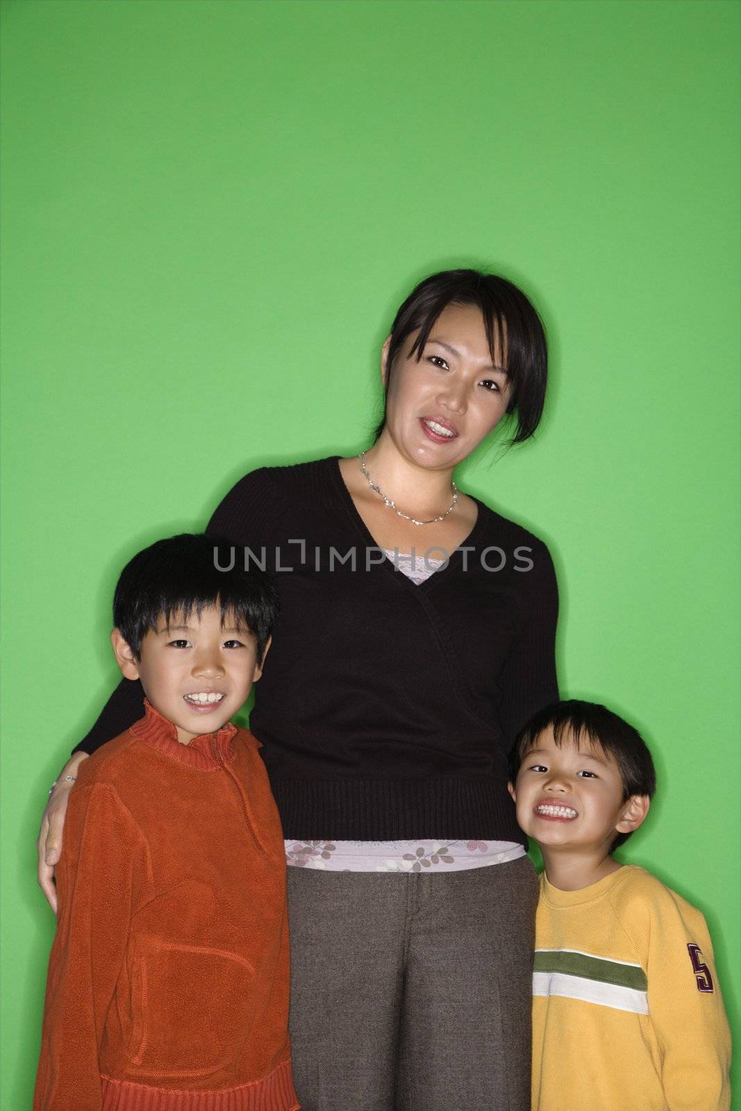 Portrait of Asian mother with two young boys smiling.