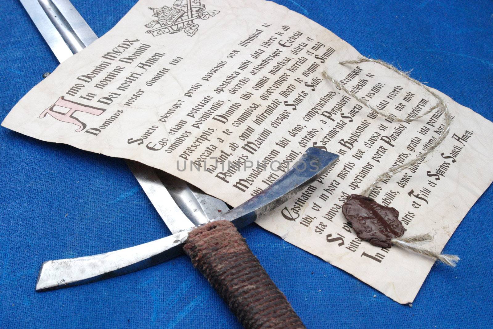 The ancient indulgence and the sword laying on a dark blue canvas