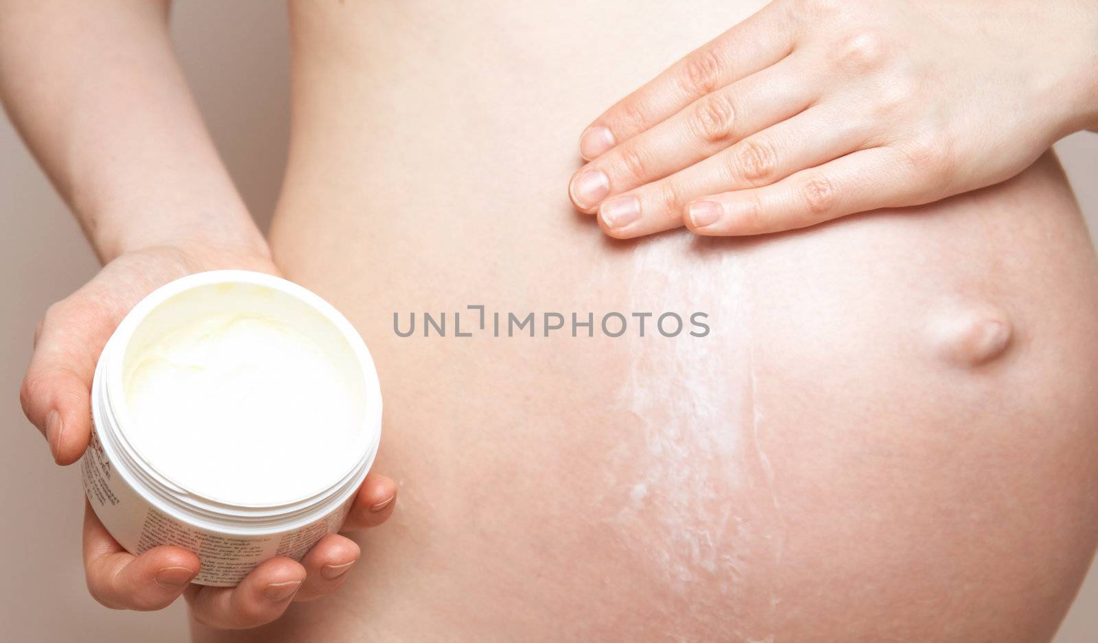pregnant woman holding body lotion by noblige