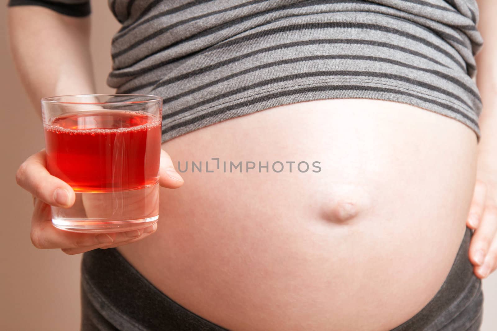 pregnant woman holding glass of red juice