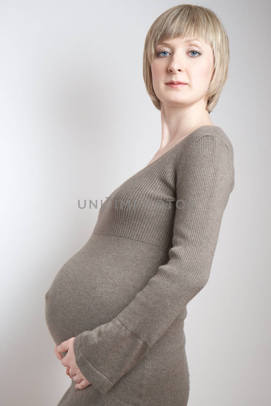 full-body portrait of a pregnant woman in a dark beige dress