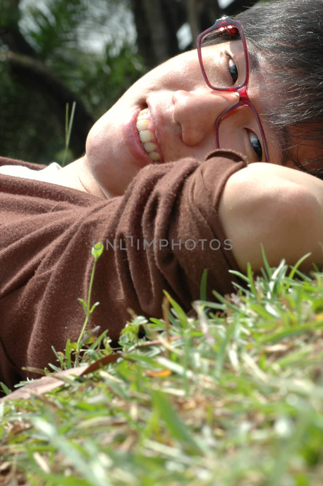 Happy young Chinese male resting on field of grass