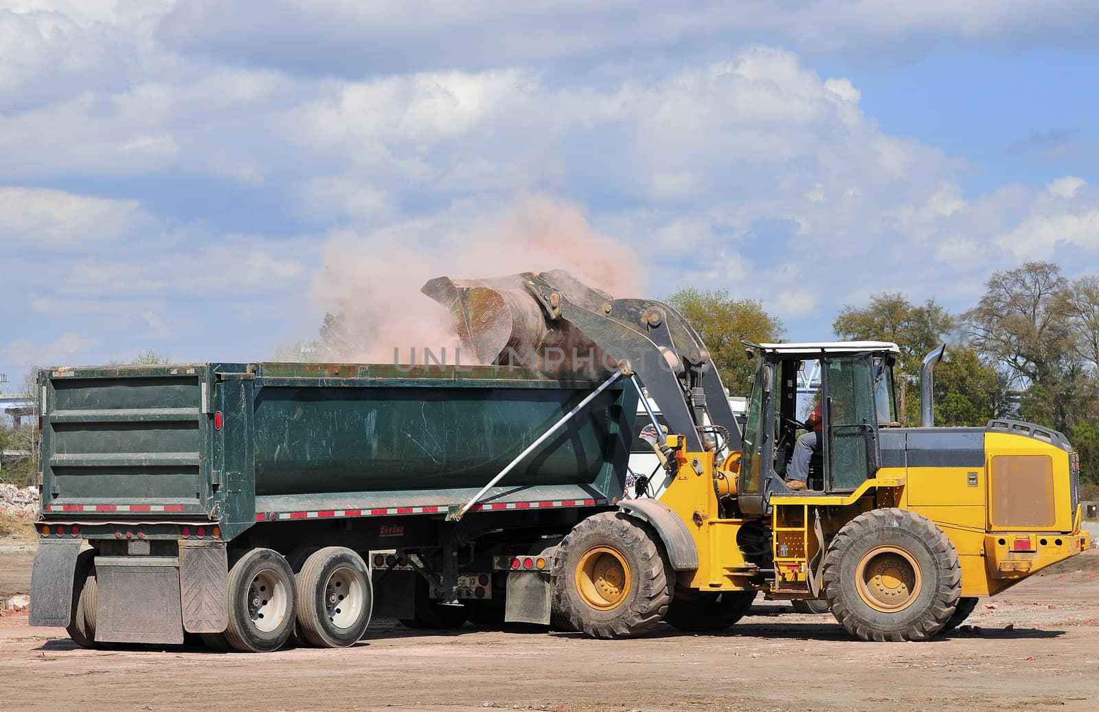 A large front end loader loading waste bricks into a dump truck