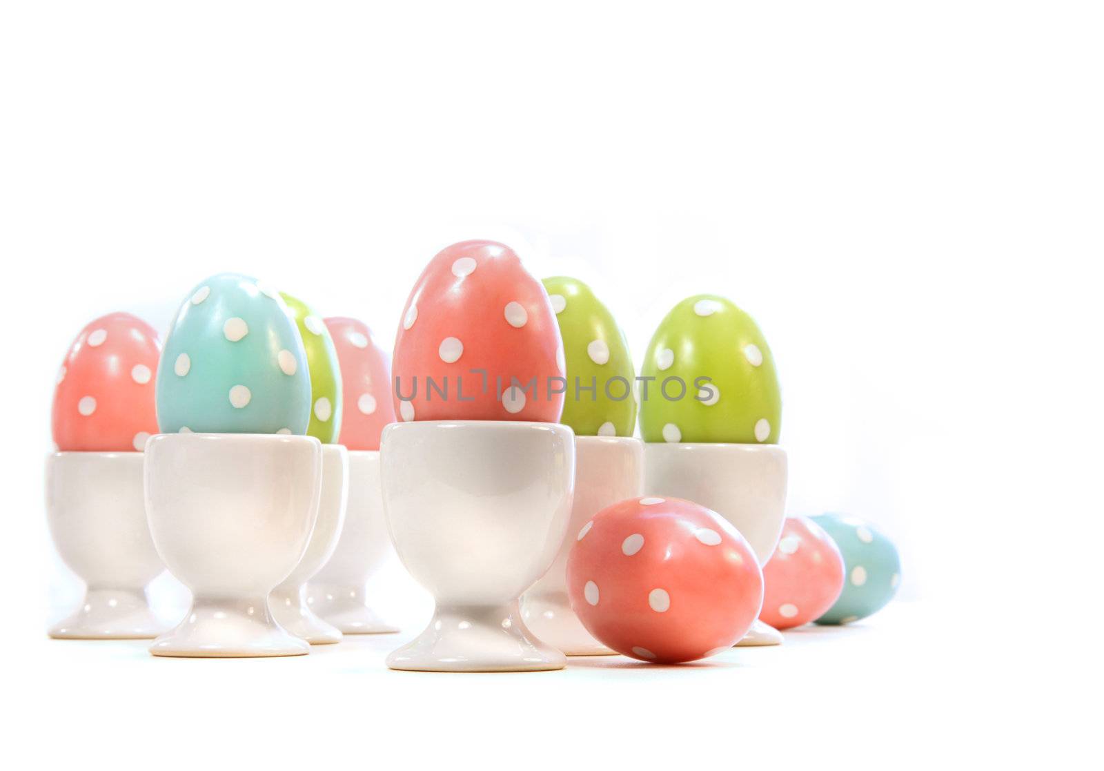 Polka dot easter eggs in cups on white background