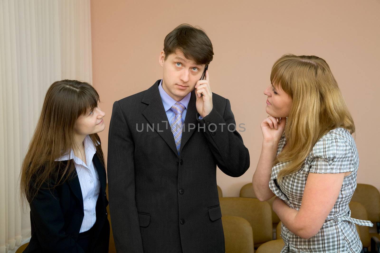 The man speaks by a mobile phone in the presence of two girls