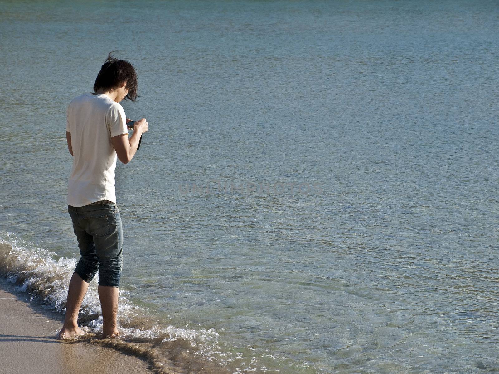 Asian man taking pictures on a beach on the Mediterranean island of Malta