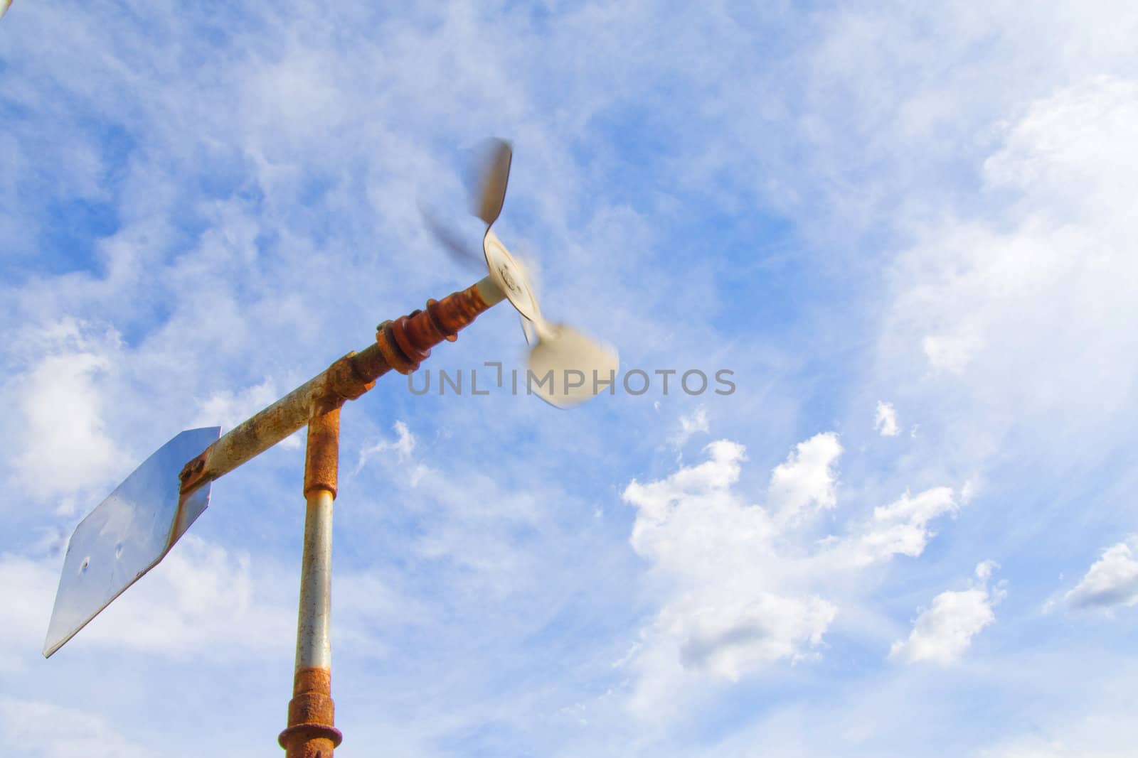 Old windmill with sky spinning in strong wind. 