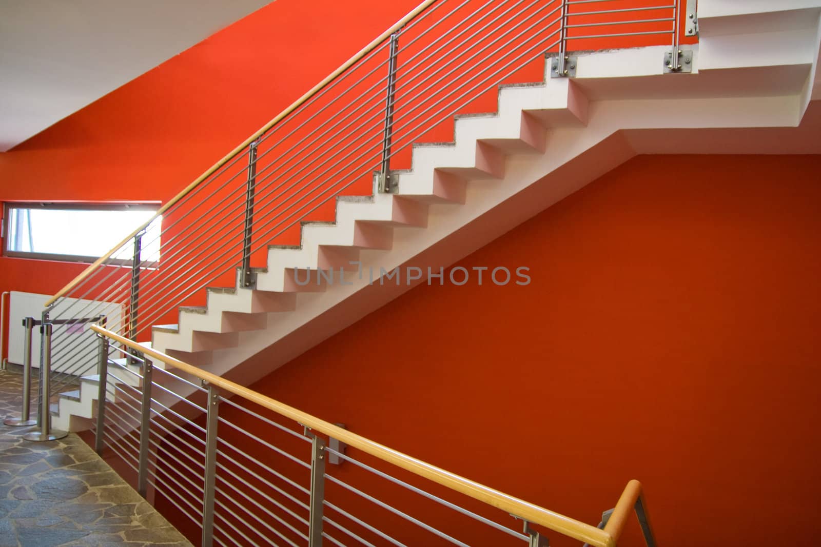 Staircase with red wall and fence going upstairs.