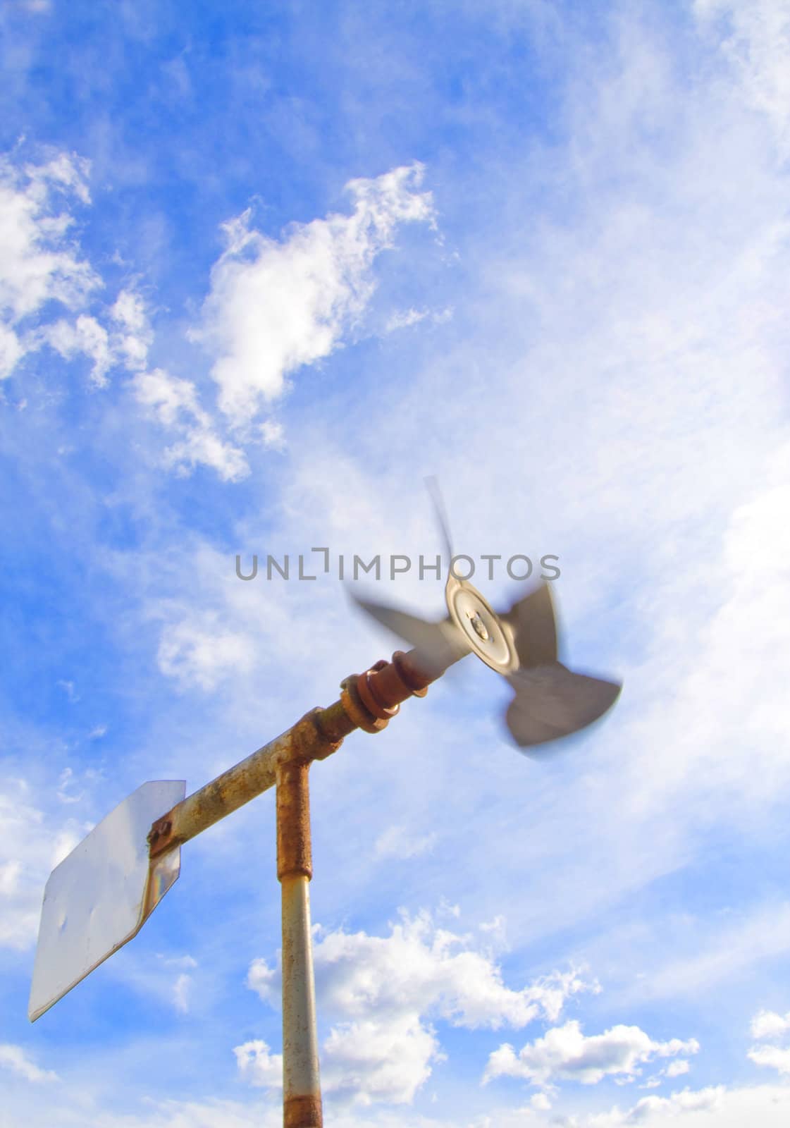 Old windmill with sky spinning in strong wind. 