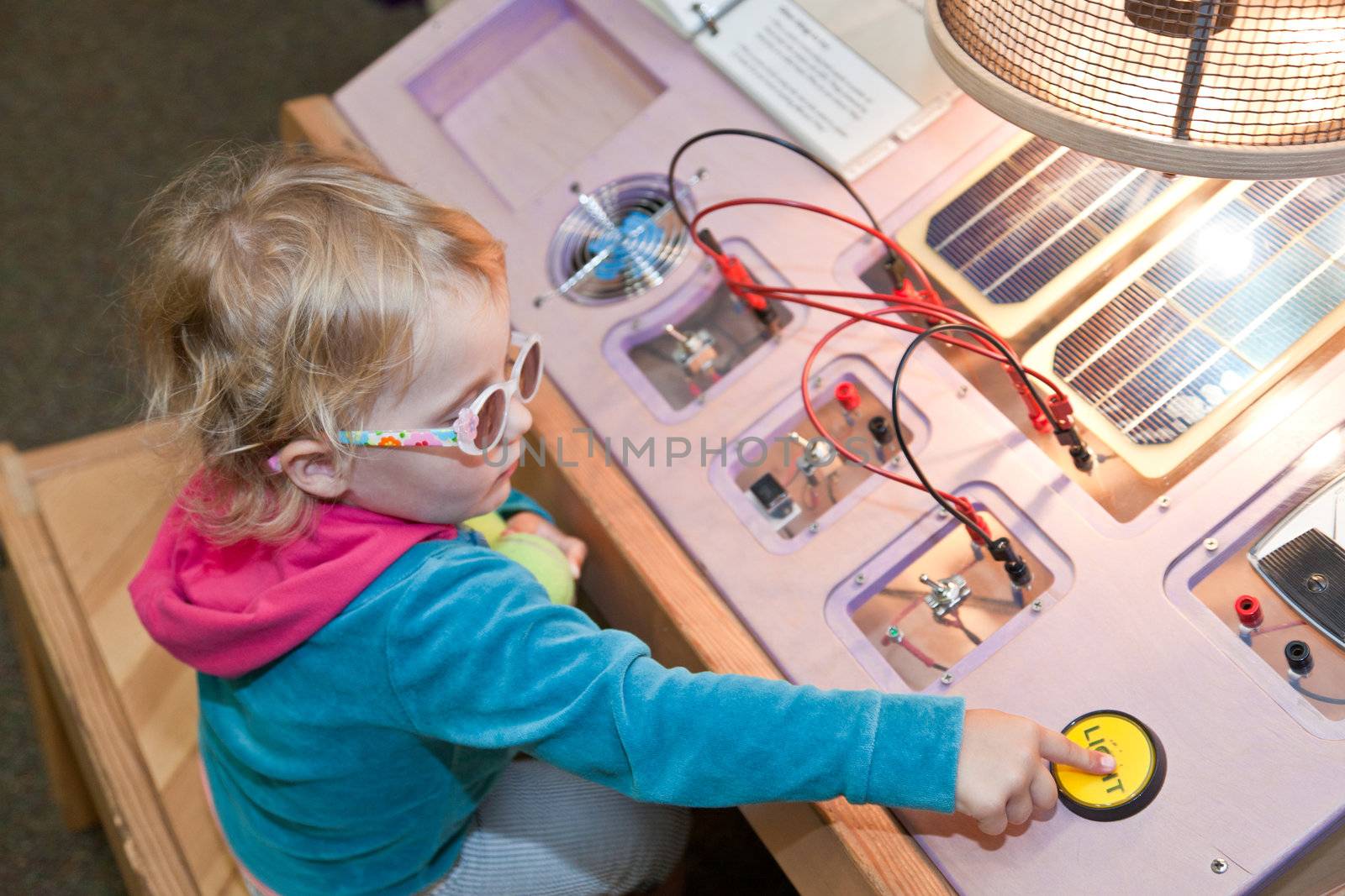 Cute little European toddler girl learning about solar power in museum