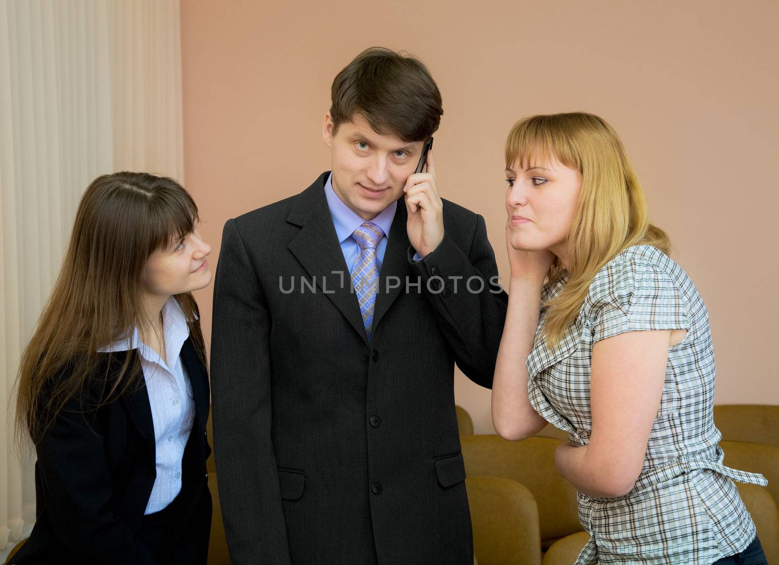 The man speaks by a mobile phone in the presence of two girls