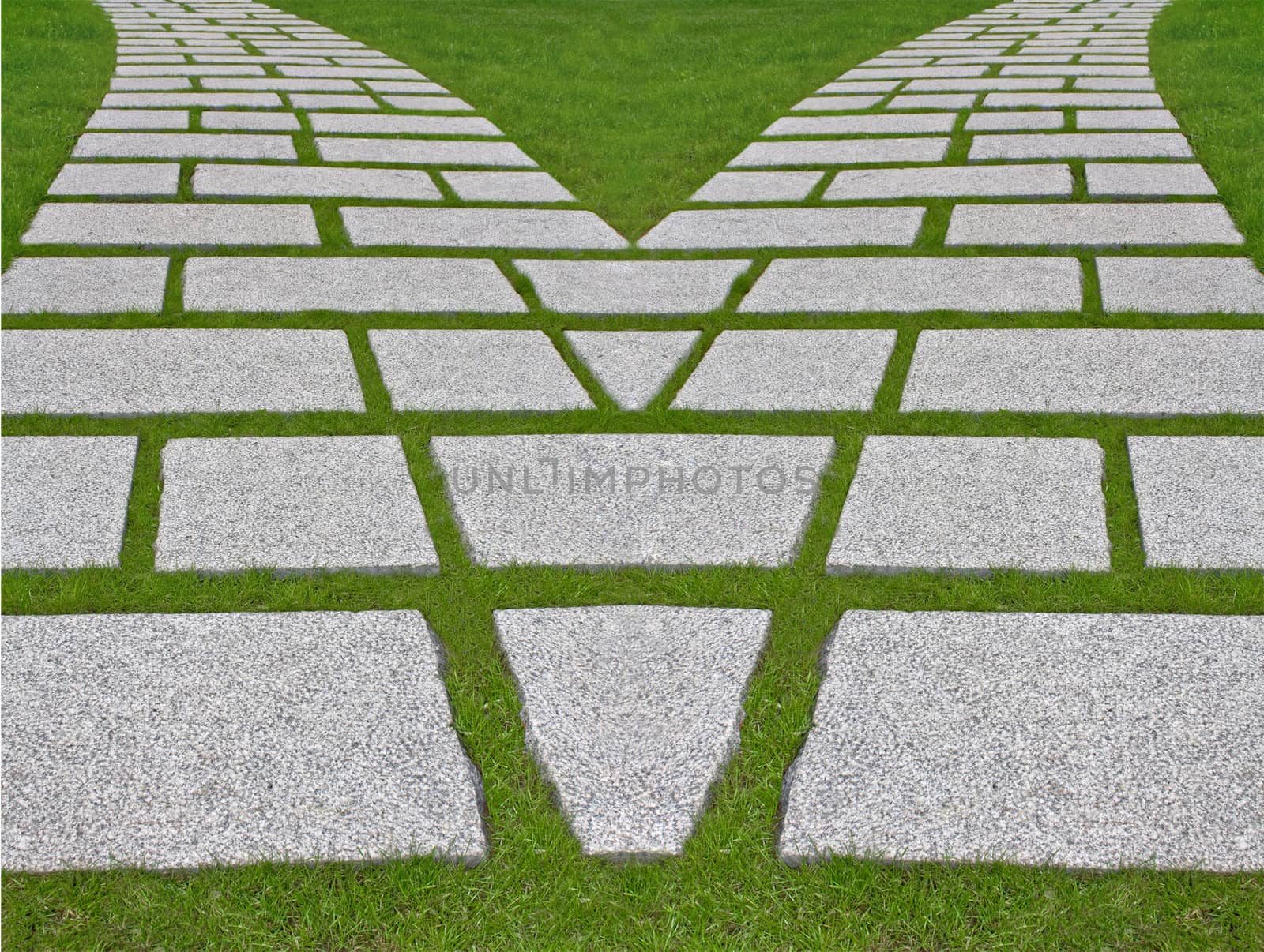 Way divergence. Granite plates on a green lawn.